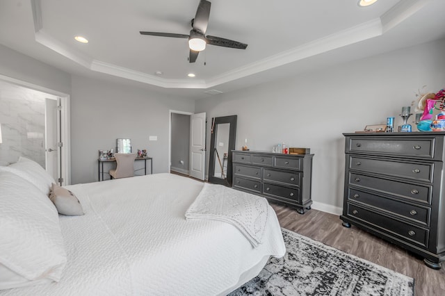 bedroom with dark hardwood / wood-style floors, ceiling fan, ornamental molding, and a tray ceiling