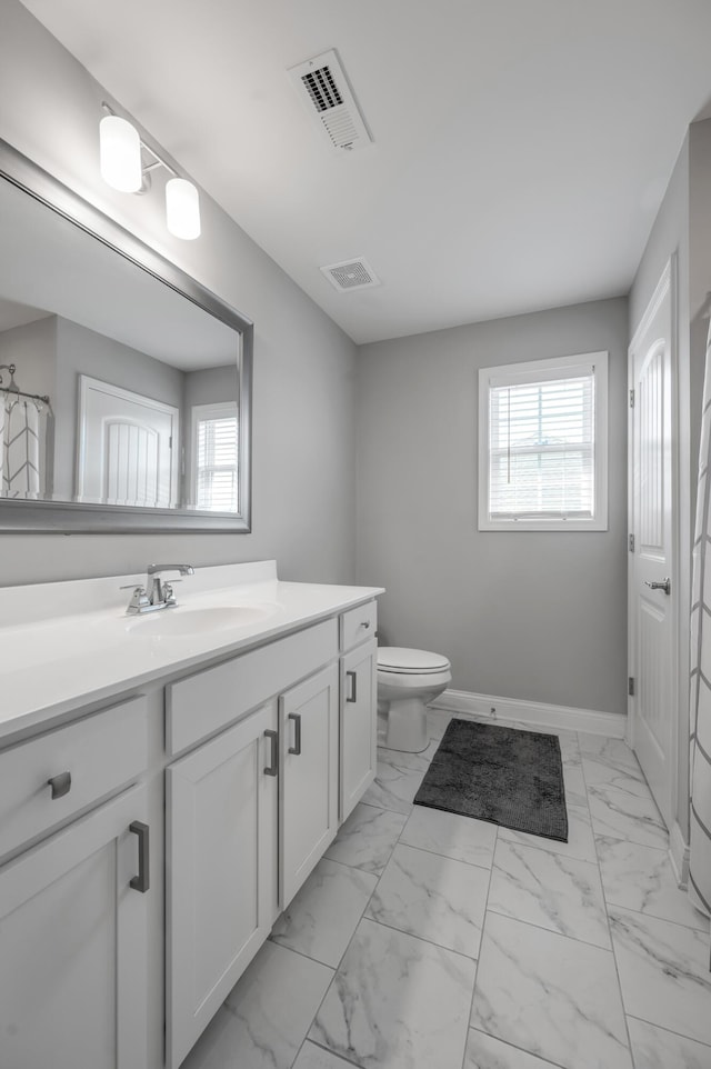 bathroom with vanity, a healthy amount of sunlight, and toilet