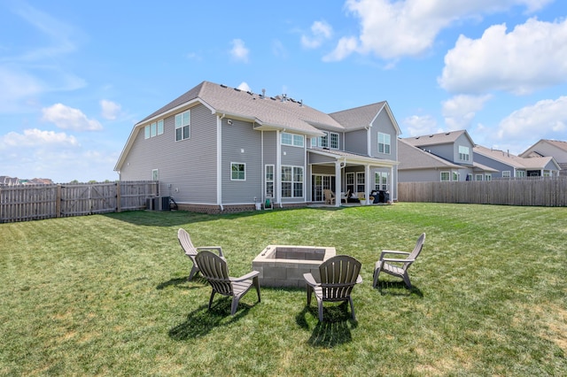 rear view of property with a lawn, a patio area, a fire pit, and central air condition unit