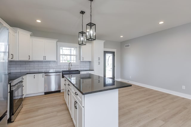 kitchen featuring tasteful backsplash, visible vents, recessed lighting, stainless steel dishwasher, and a kitchen island