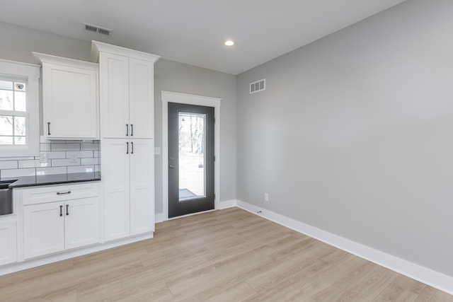 kitchen with light wood-style floors, visible vents, white cabinetry, and dark countertops
