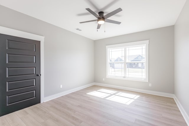 spare room with light wood-style flooring, ceiling fan, baseboards, and visible vents