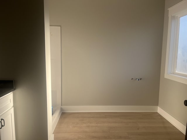 clothes washing area featuring laundry area, light wood-type flooring, and baseboards