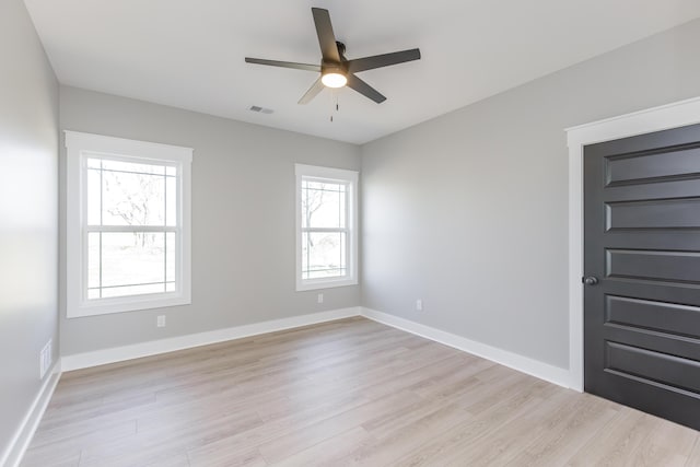 empty room featuring a wealth of natural light, light wood-type flooring, and a ceiling fan