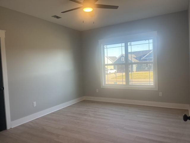 empty room featuring visible vents, ceiling fan, baseboards, and wood finished floors