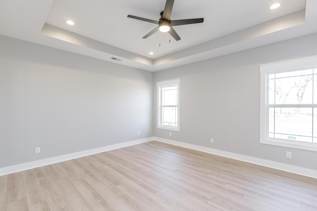 unfurnished room featuring a raised ceiling, ceiling fan, recessed lighting, and light wood-style flooring