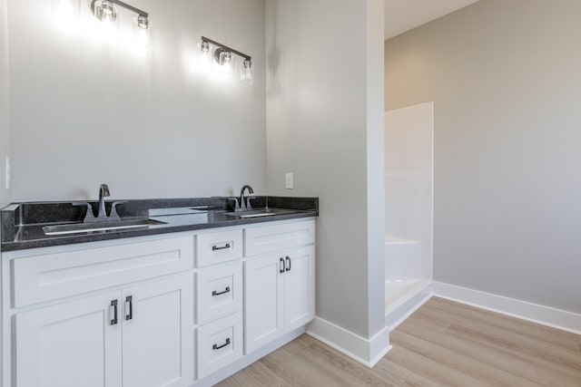 bathroom featuring wood finished floors, a sink, and baseboards