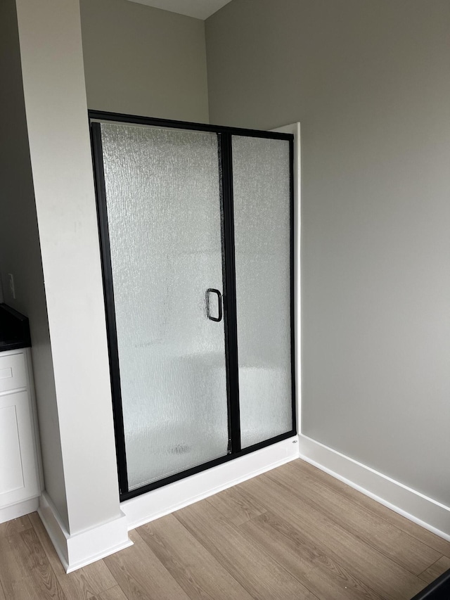 bathroom featuring a shower stall, baseboards, and wood finished floors