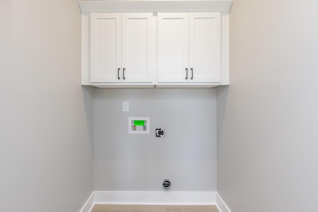 clothes washing area with hookup for an electric dryer, baseboards, washer hookup, and cabinet space