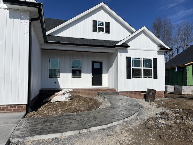 doorway to property with covered porch, roof with shingles, and crawl space