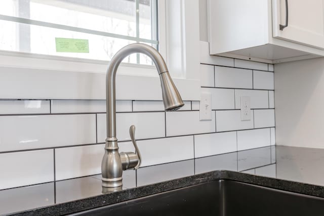 interior details with dark stone countertops, decorative backsplash, a sink, and white cabinets
