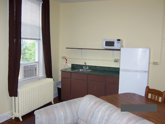 kitchen with cooling unit, radiator, white appliances, and sink