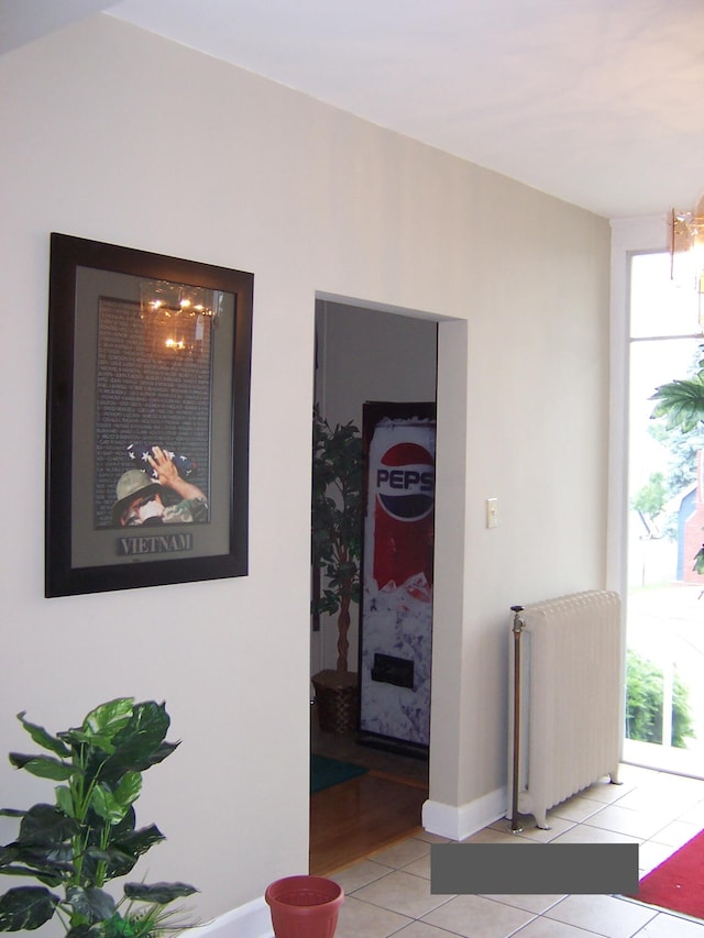 corridor with light tile patterned floors and radiator heating unit