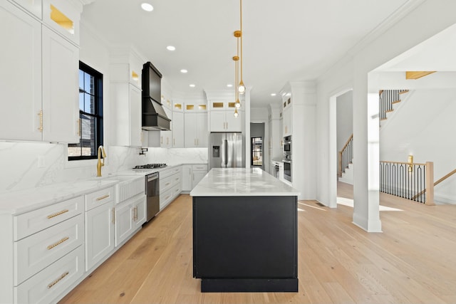 kitchen featuring sink, white cabinetry, hanging light fixtures, appliances with stainless steel finishes, and a kitchen island