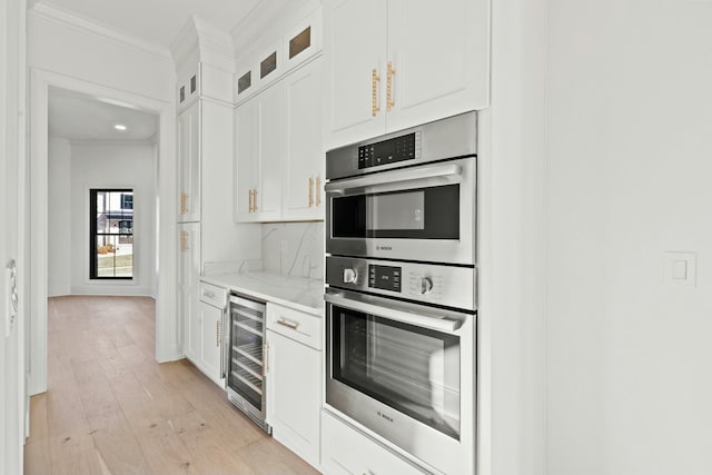 kitchen with wine cooler, white cabinetry, ornamental molding, stainless steel double oven, and light stone countertops