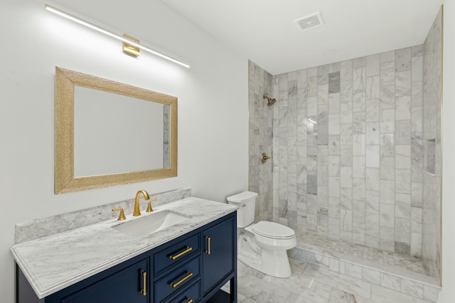 bathroom with vanity, toilet, and a tile shower