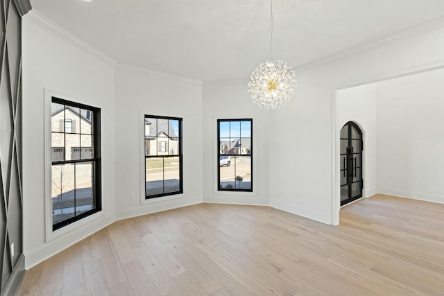 empty room featuring crown molding, a chandelier, and light wood-type flooring