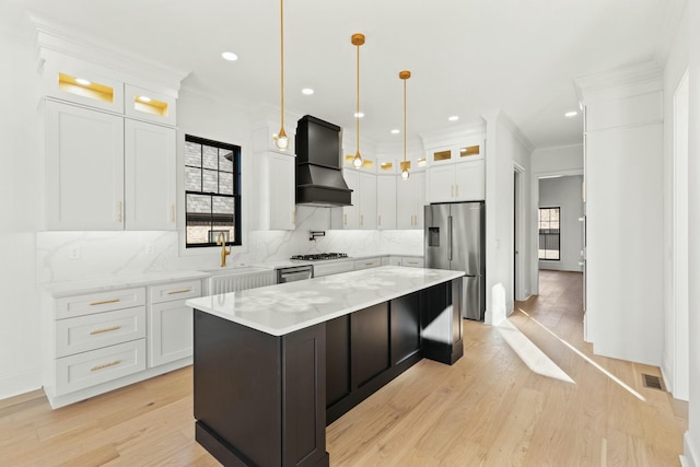 kitchen featuring stainless steel appliances, custom range hood, white cabinets, and a center island