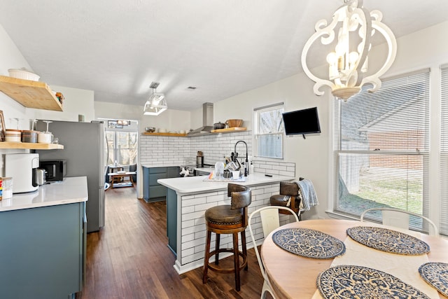 kitchen with dark hardwood / wood-style floors, tasteful backsplash, a kitchen bar, a chandelier, and blue cabinetry