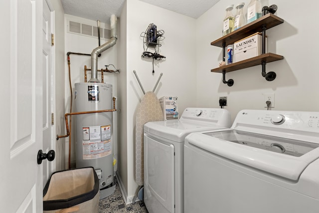 washroom featuring water heater, separate washer and dryer, and a textured ceiling