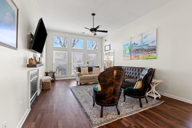 living room with dark hardwood / wood-style flooring, ceiling fan, and a textured ceiling