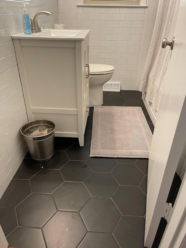 bathroom featuring tile walls, a shower with shower curtain, toilet, vanity, and tile patterned floors