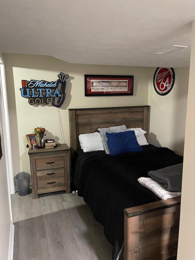 bedroom featuring a textured ceiling and light hardwood / wood-style flooring