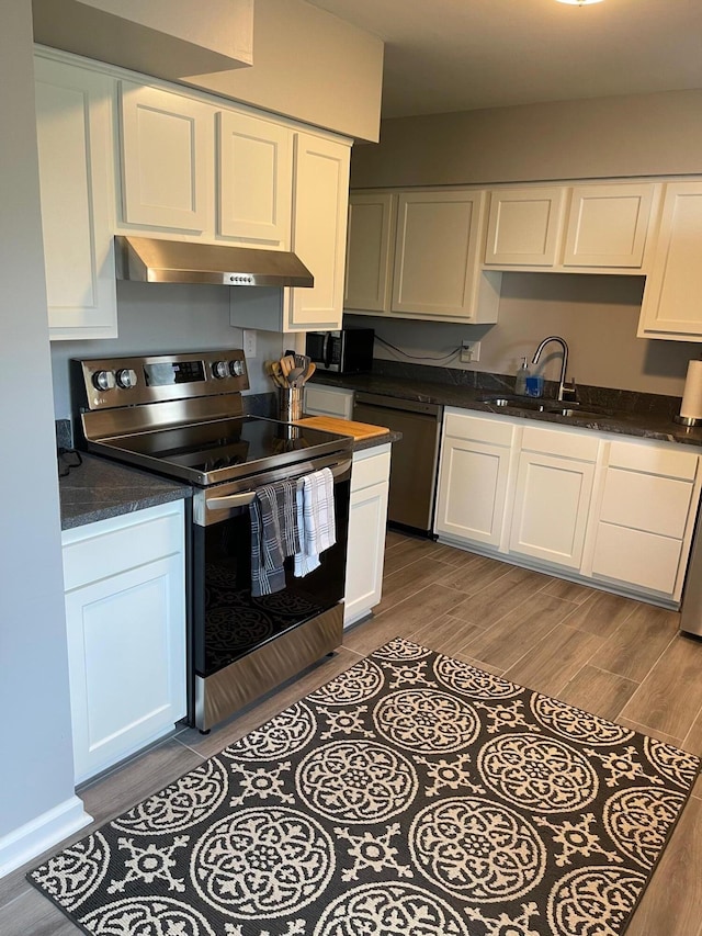 kitchen featuring black microwave, stainless steel range with electric cooktop, under cabinet range hood, white cabinetry, and a sink