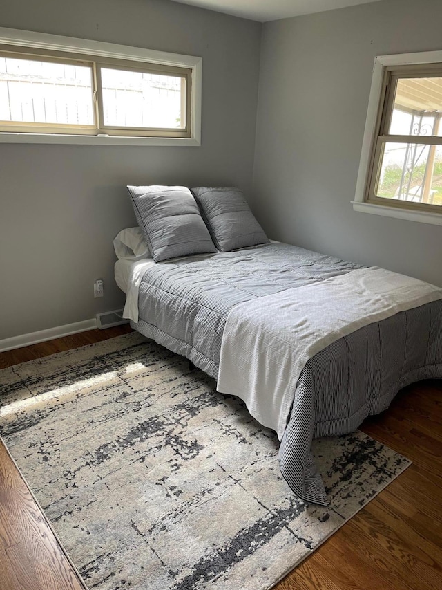 bedroom featuring visible vents, baseboards, and wood finished floors