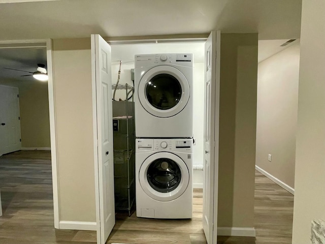 clothes washing area featuring stacked washer and dryer, wood-type flooring, and ceiling fan