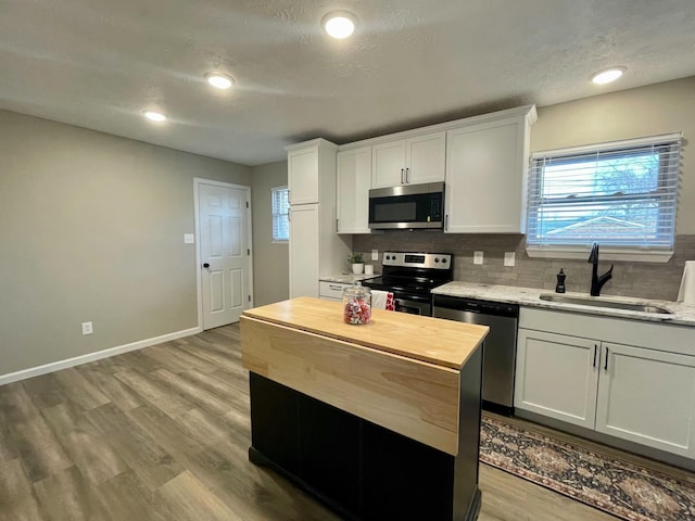 kitchen featuring stainless steel appliances, sink, white cabinets, and light hardwood / wood-style flooring