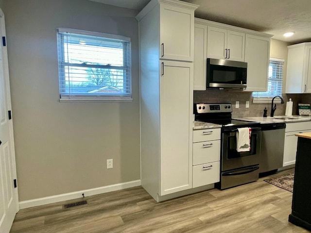 kitchen with tasteful backsplash, appliances with stainless steel finishes, sink, and white cabinets