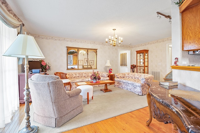 living room featuring an inviting chandelier, a textured ceiling, and light wood-type flooring