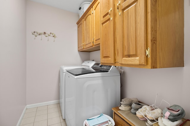 laundry room featuring separate washer and dryer, light tile patterned floors, and cabinets