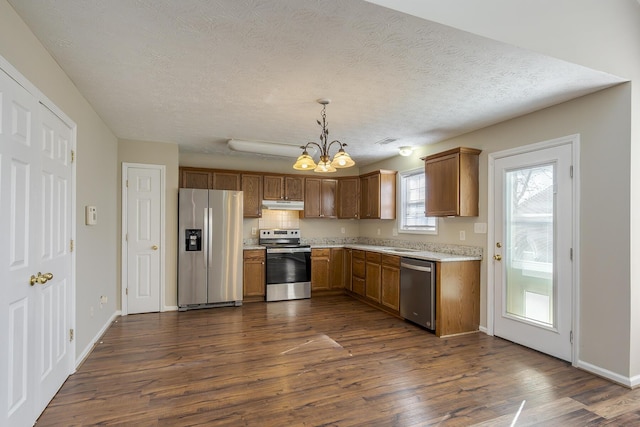 kitchen featuring decorative light fixtures, a textured ceiling, appliances with stainless steel finishes, dark hardwood / wood-style flooring, and a notable chandelier