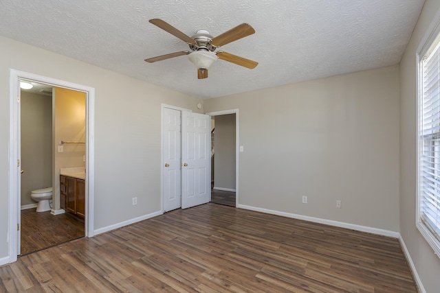 unfurnished bedroom with ceiling fan, dark hardwood / wood-style floors, connected bathroom, and a textured ceiling