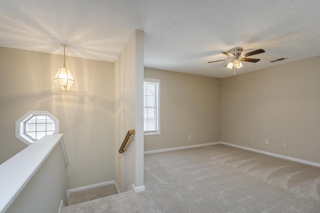 stairway featuring ceiling fan, carpet flooring, and a textured ceiling