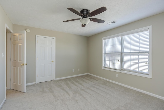 carpeted spare room featuring ceiling fan and a textured ceiling