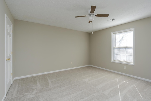 unfurnished room featuring ceiling fan, light colored carpet, and a textured ceiling