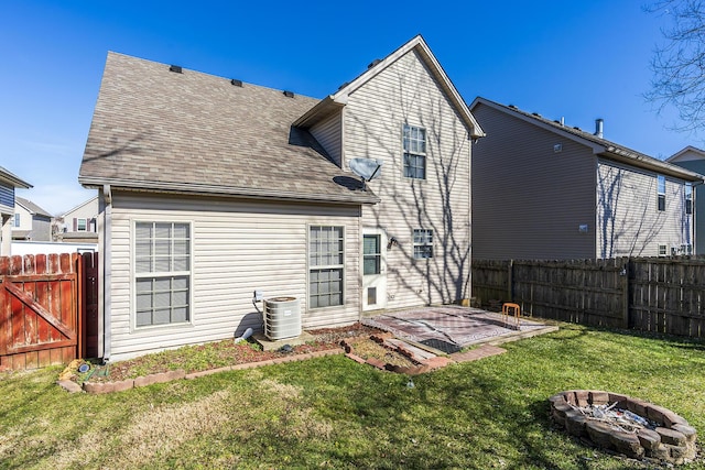 back of property with a yard, a patio area, central air condition unit, and an outdoor fire pit