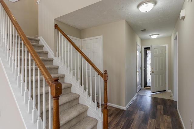 foyer entrance with dark hardwood / wood-style floors and a textured ceiling