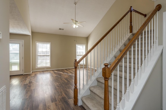 staircase with wood-type flooring, a textured ceiling, and ceiling fan