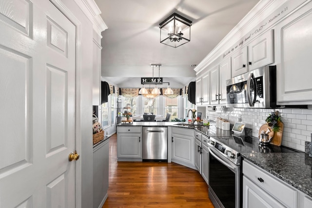 kitchen featuring pendant lighting, white cabinetry, sink, dark hardwood / wood-style flooring, and stainless steel appliances