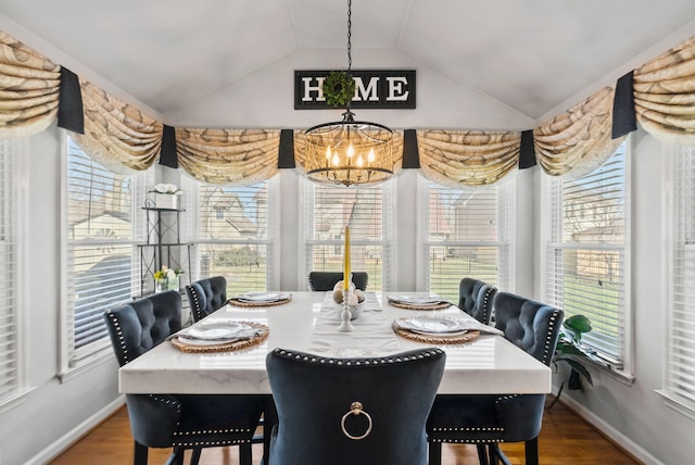 dining area featuring vaulted ceiling, a wealth of natural light, hardwood / wood-style floors, and a chandelier