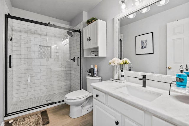 bathroom with a shower with door, vanity, hardwood / wood-style floors, and toilet