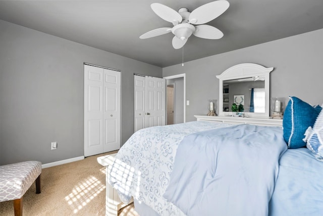 bedroom featuring two closets, ceiling fan, and carpet flooring