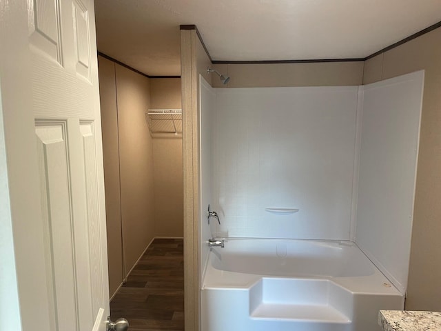 bathroom featuring crown molding, wood-type flooring, and washtub / shower combination