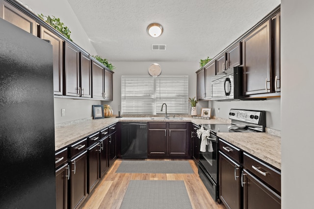 kitchen with sink, dark brown cabinetry, black appliances, a textured ceiling, and light wood-type flooring