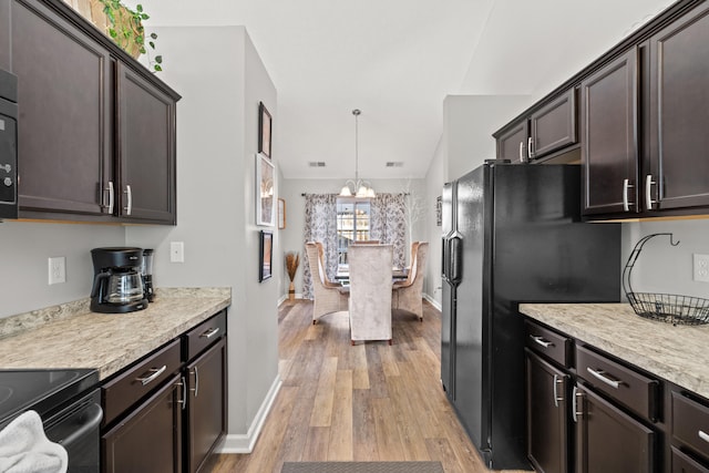 kitchen featuring pendant lighting, dark brown cabinets, light hardwood / wood-style flooring, and black fridge