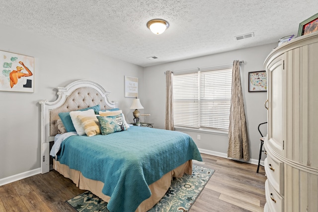 bedroom with hardwood / wood-style floors and a textured ceiling